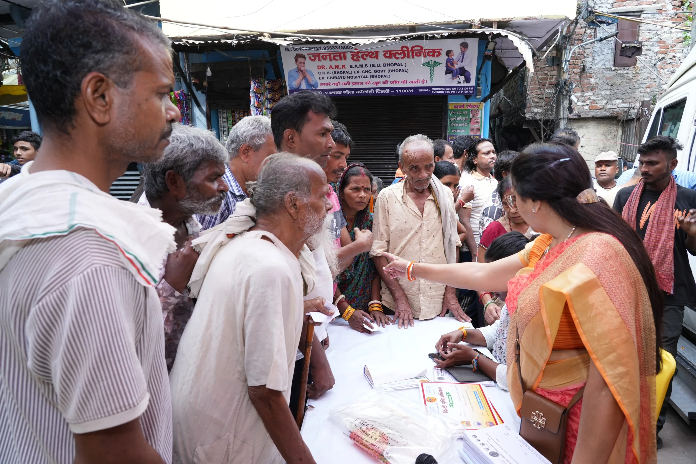 A guest offers marigold flowers at a small puja beside the mobile eye clinic as others look on.